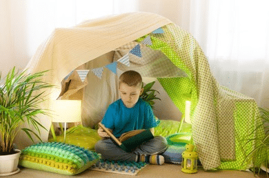 Un enfant de CP fait de la lecture sous un tipi dans sa chambre